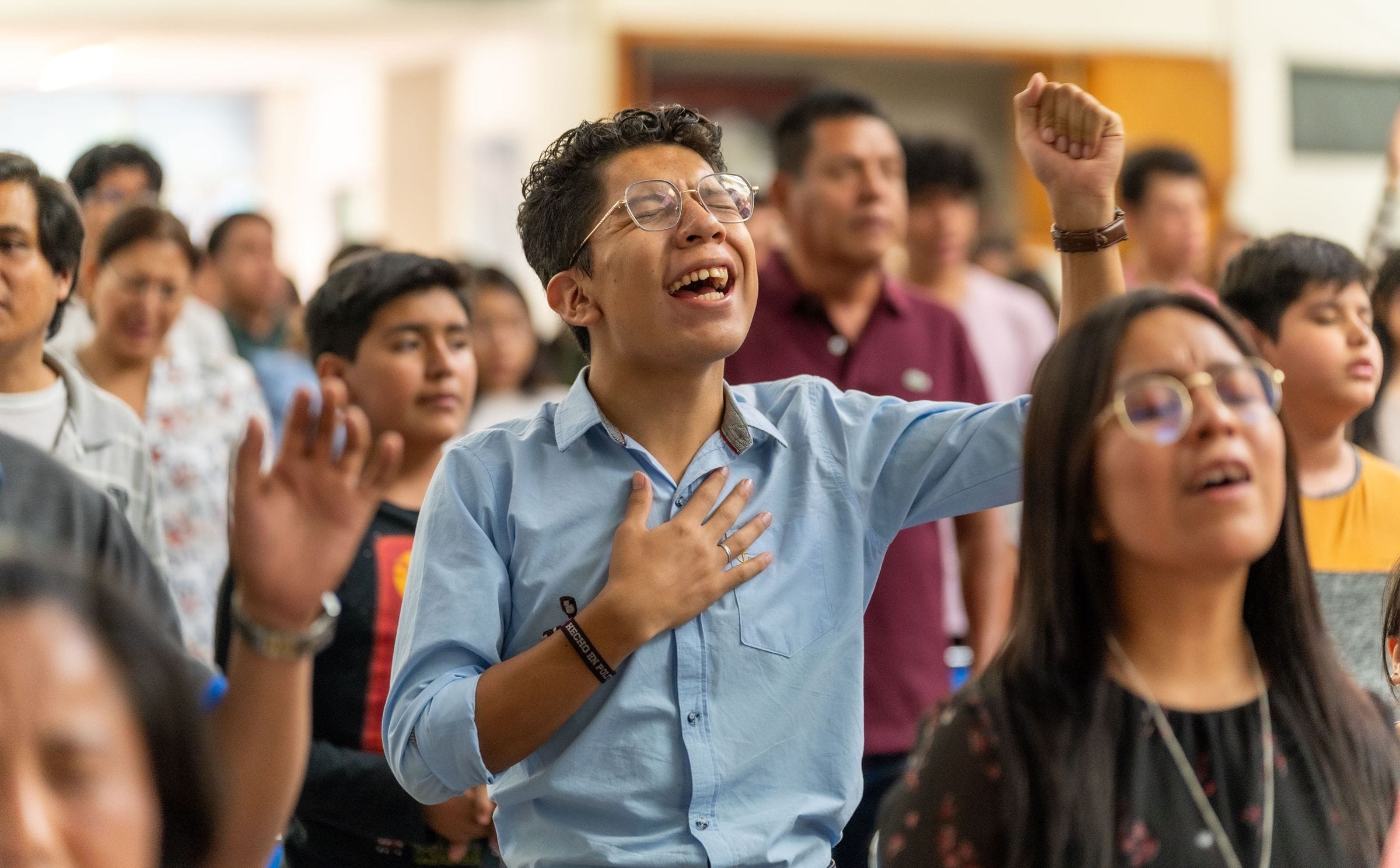 Un joven canta con la mano en el corazón durante la alabanza.